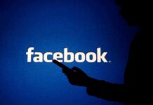 silhouette holding a smartphone in front of Facebook logo
