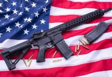 AR-style rifle on American flag with magazines and bullets