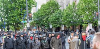 group of masked protesters walking through a city street