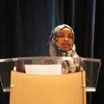 Woman in hijab speaking at a podium