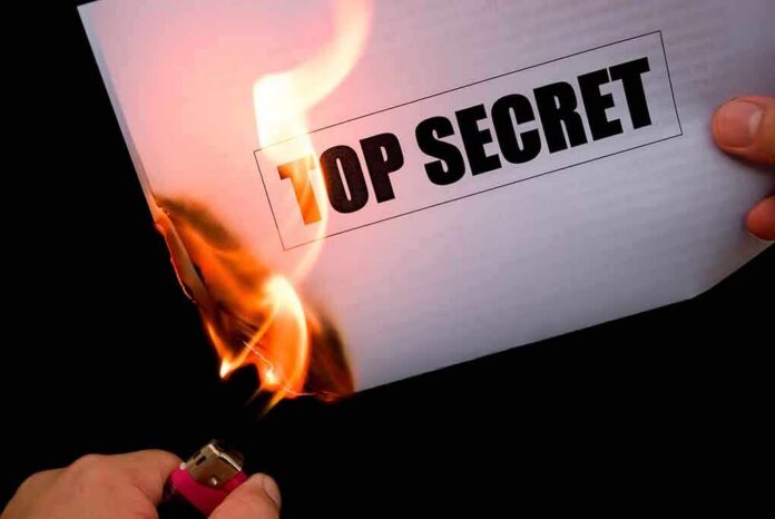 A hand holding a lighter igniting a paper labeled TOP SECRET as it catches fire