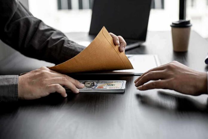 shutterstock_1925198729 Hands exchanging cash in an envelope at a desk