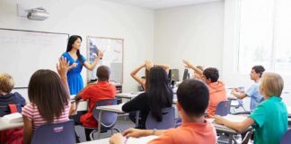 Teacher leading classroom discussion with students raising hands