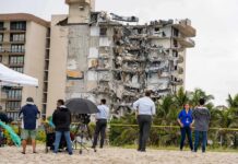 Partially collapsed beachfront apartment building with onlookers