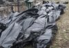 Black plastic bags piled outdoors near metal fencing
