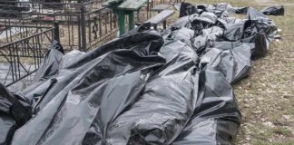 Black plastic bags piled outdoors near metal fencing