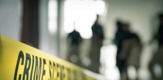 Crime scene tape with investigators in the background
