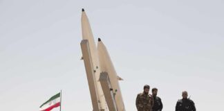 Soldiers stand beside large missiles at an outdoor display