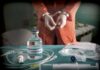 Medical vials and IV lines on a table with a handcuffed person in the background